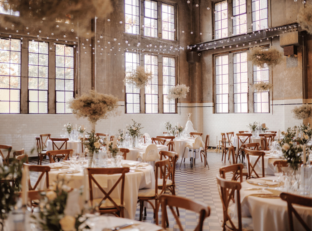 Hochzeitsdekoration mit runden Tischen und Schleierkrautwolken in der Alten Maschinenhalle