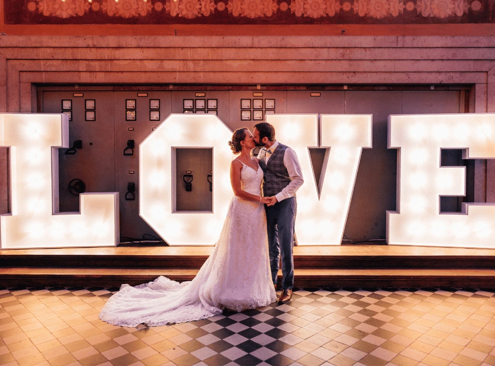 Brautpaar küsst sich vor den LOVE-Buchstaben in der Alten Maschinenhalle Solingen