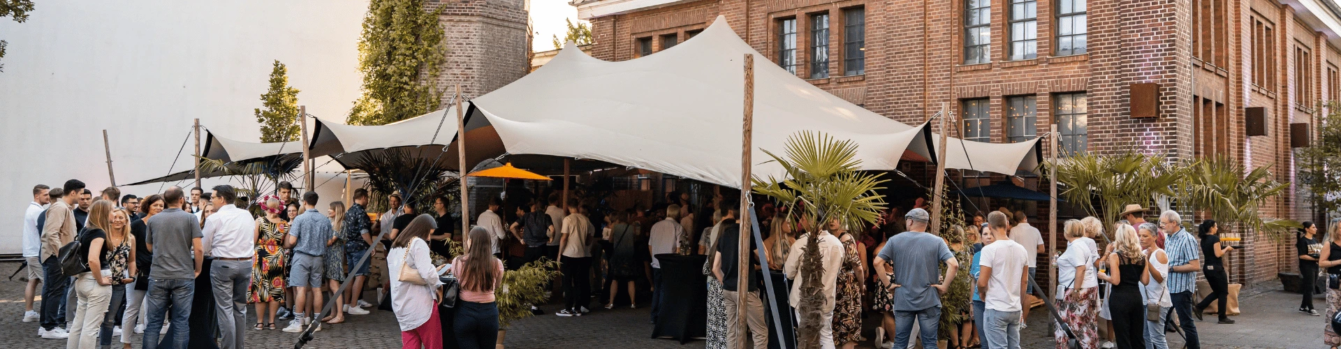 Außenbereich der Alten Maschinenhalle Solingen mit Zelt, Stehtischen und Gästen bei einem Firmenevent am Tag