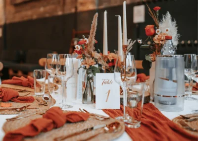 Hochzeitstisch mit Tischläufern, Blumenarrangements und warmen Natur- und Rosttönen in der Alten Maschinenhalle Solingen.