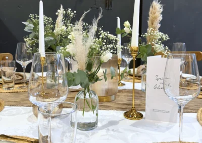 Detailaufnahme einer Hochzeitstischdekoration mit Glasvasen, Goldkerzenständern und Menükarte in der Alten Maschinenhalle Solingen.