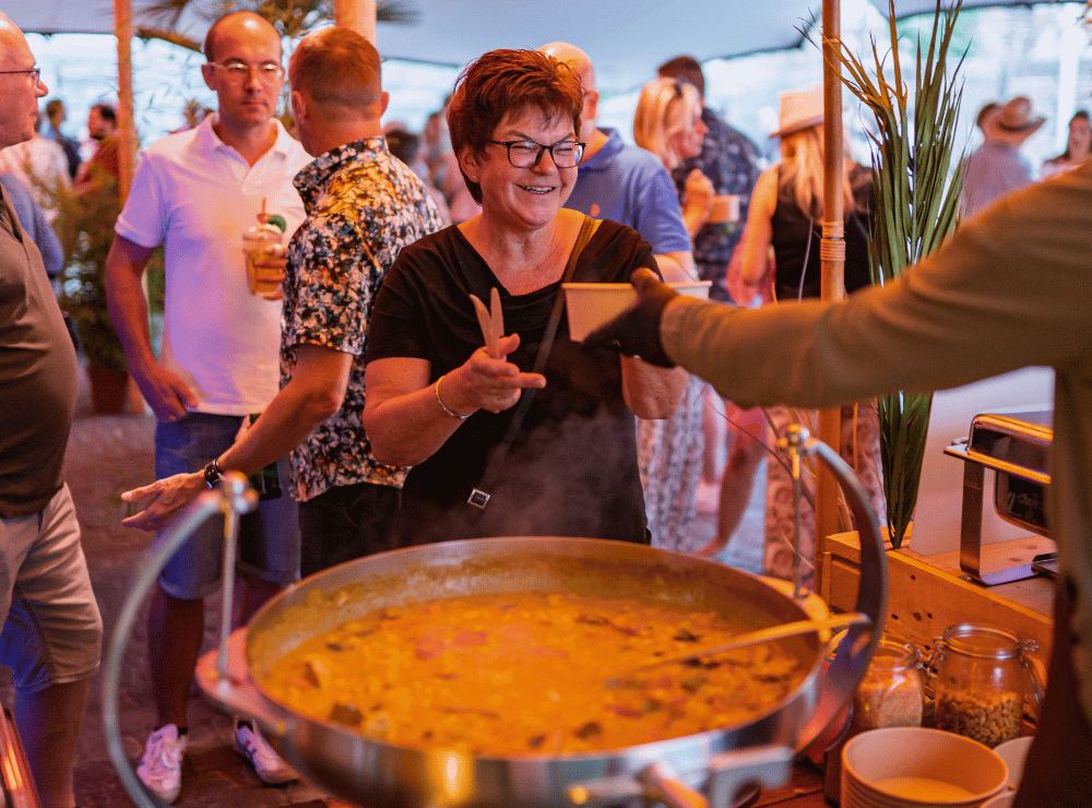 Eine Frau nimmt eine frisch zubereitete Mahlzeit an einem Streetfood-Stand im Außenbereich entgegen