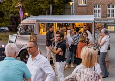 Ein Food Truck steht vor der Alten Maschinenhalle Solingen im Außenbereich, Gäste stehen davor und genießen ihr Streetfood-Catering.