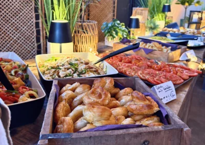 Frisches Catering-Buffet mit Börek im Holzkistchen, Nudelsalat, Tomaten und Gegrilltem auf einer Feier.