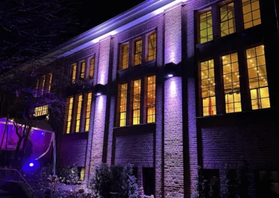 Historische Backsteinfassade der Alten Maschinenhalle am Abend in lila Licht erstrahlt.